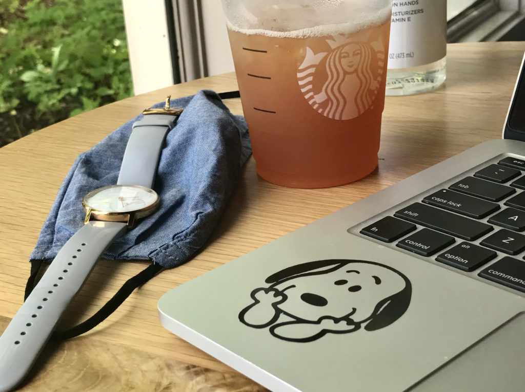 A laptop, watch, and iced tea on a Starbucks table.