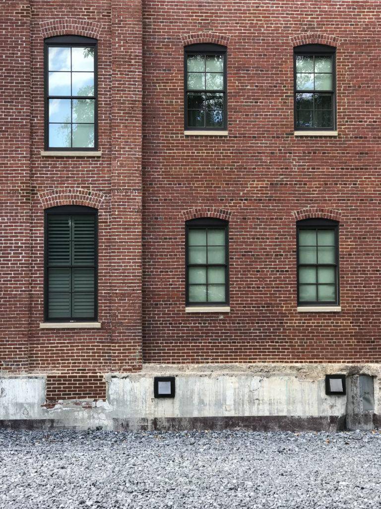 An old brick factory wall, with windows.