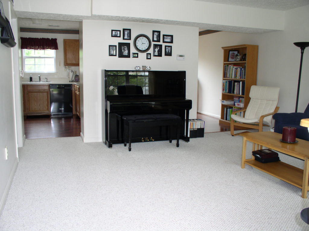 A black upright piano in a living room.