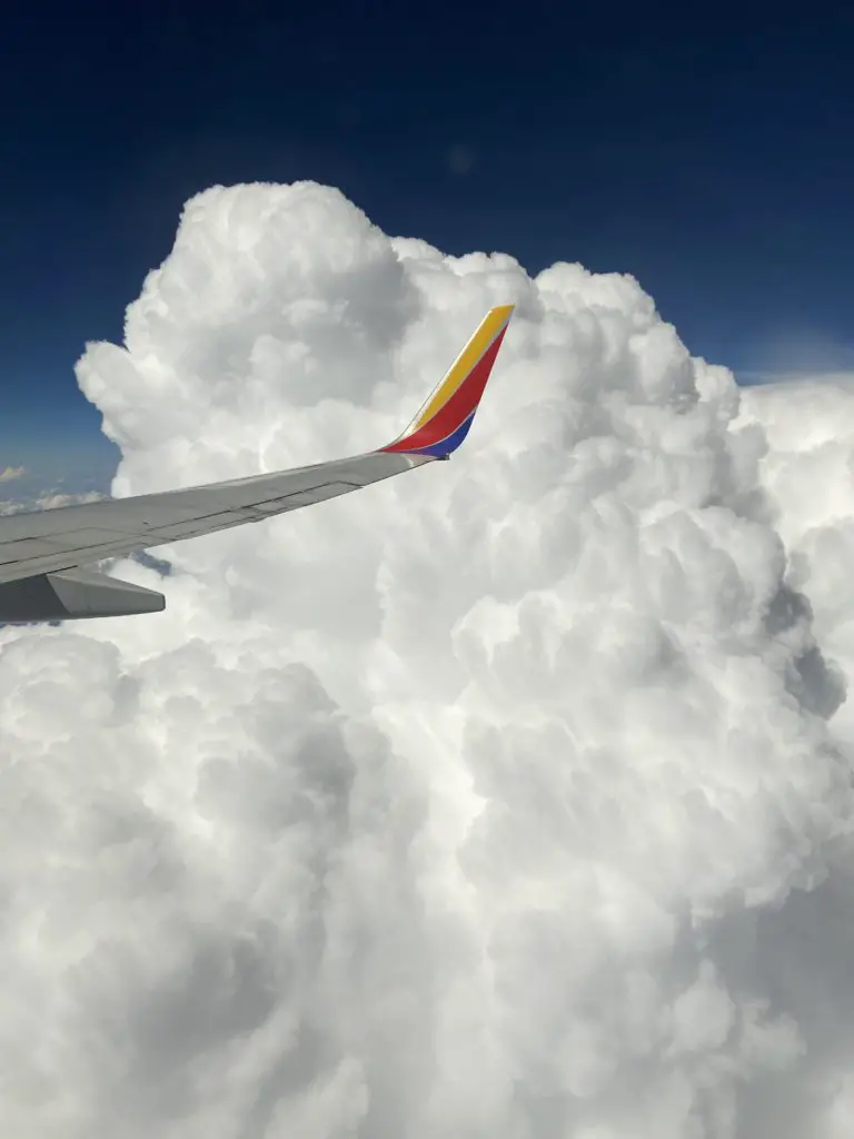 plane wing near a puffy cloud.